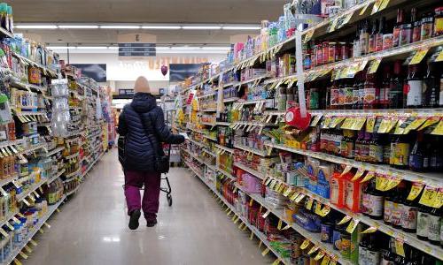 A person walks down the aisle of a grocery store.